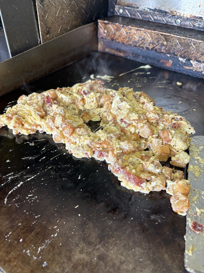 Eggs, potatoes and bacon cooking on the flat-top griddle