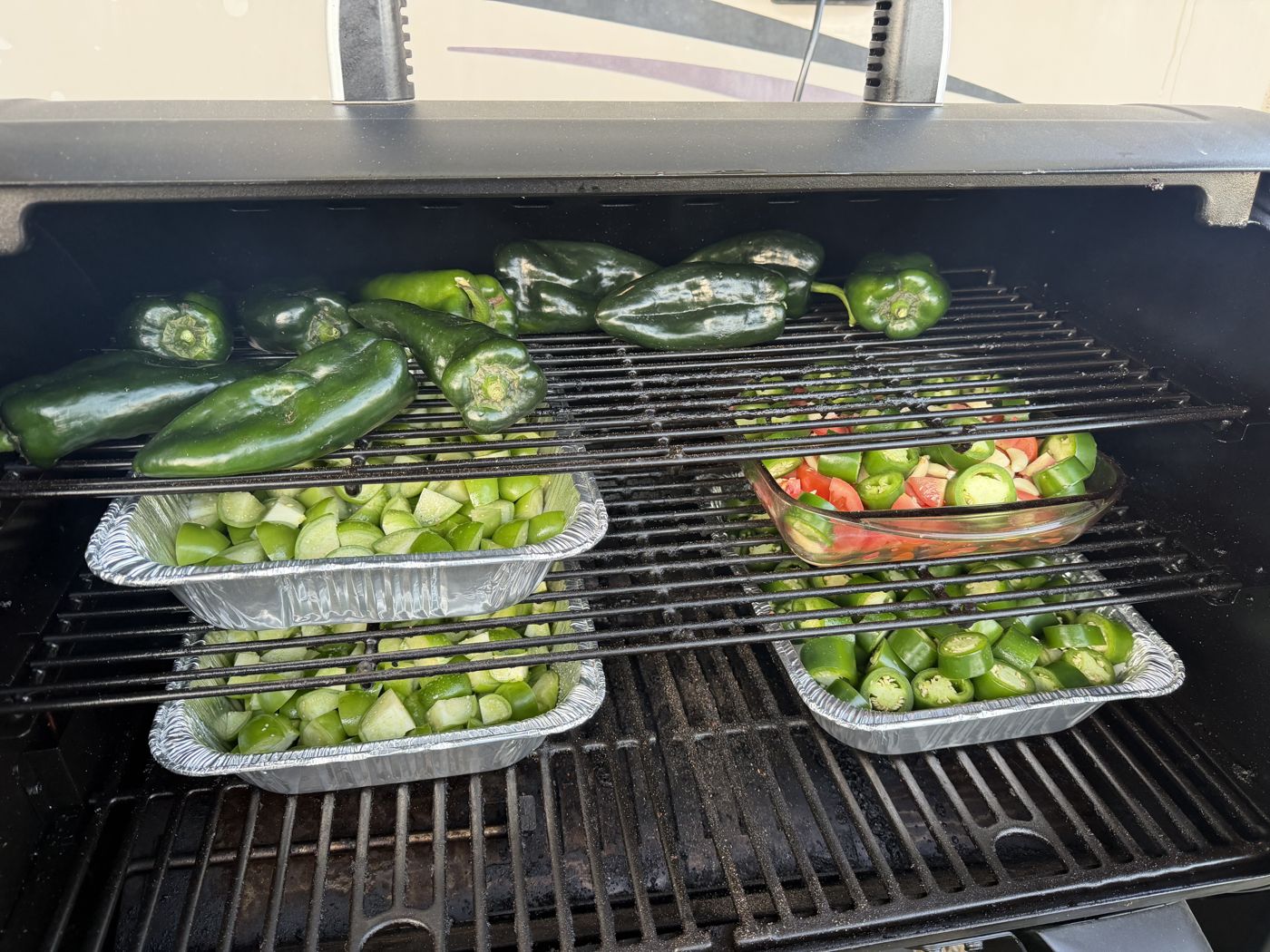 Poblanos, tomatillos, jalapeños and tomatoes roasting on the smoker