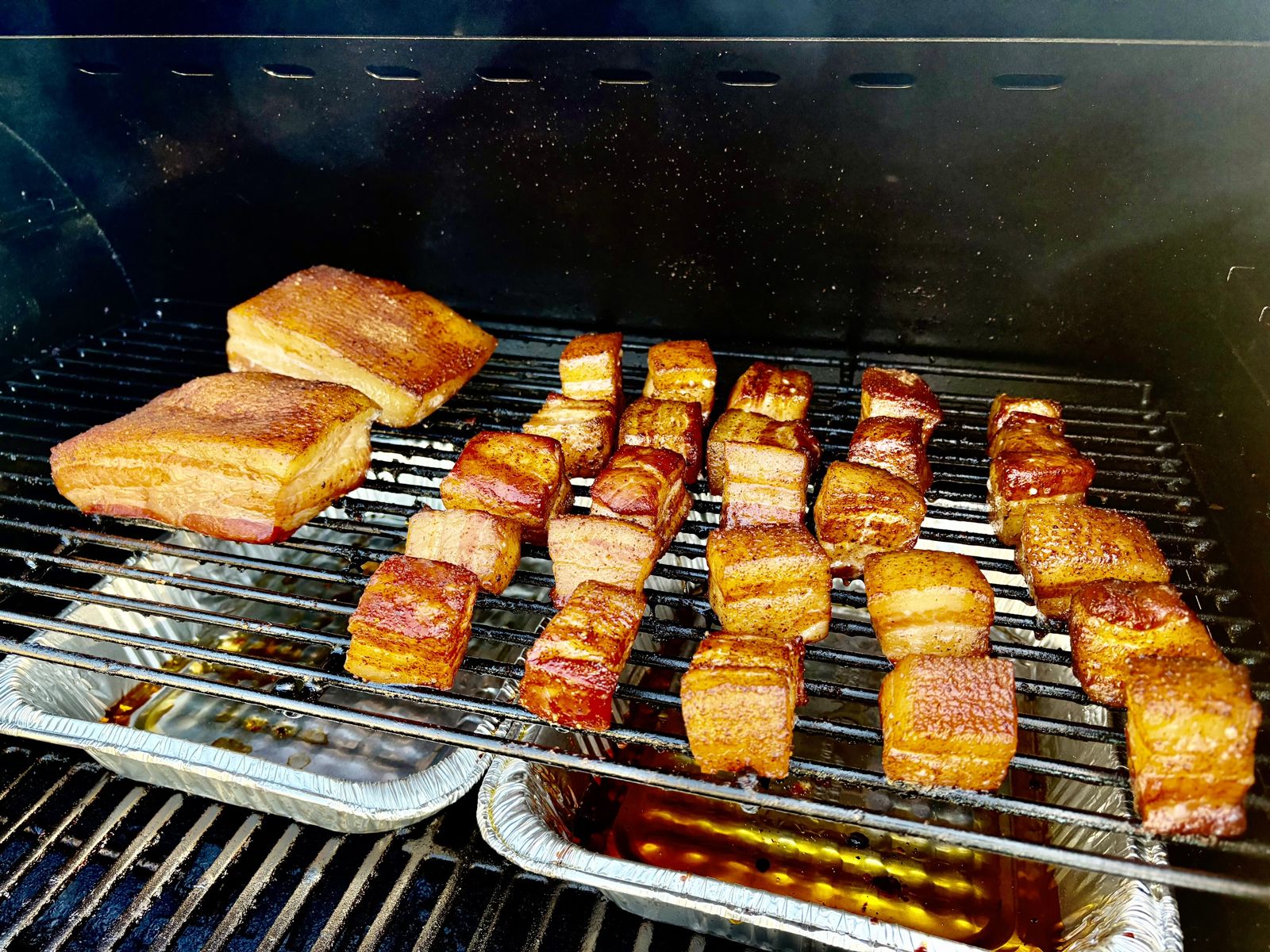 Seasoned pork belly cubes on the smoker grate